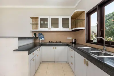 a kitchen with white cabinets and a sink and a window at Villa Raja Seminyak by KING in Seminyak