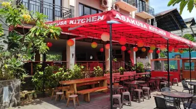 a restaurant with tables and chairs under a red umbrella at The Aroma's of Bali Hotel & Residence in Legian