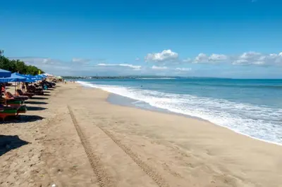 a beach with chairs and umbrellas and the ocean at Hadi Poetra Hotel in Kuta