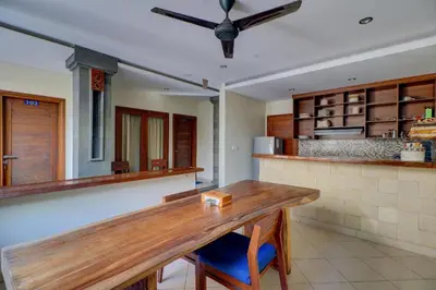 a kitchen with a wooden table and a counter at OYO Life 92852 Singgah Hotel Legian in Legian