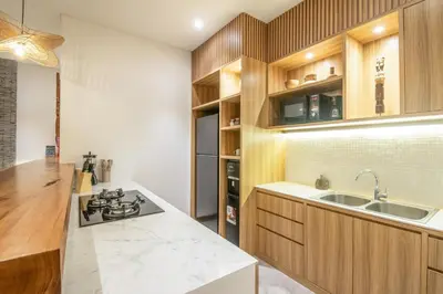 a kitchen with wooden cabinets and a stove top oven at Coastal Elegance 4BR Villa, 400m to Finns in Canggu