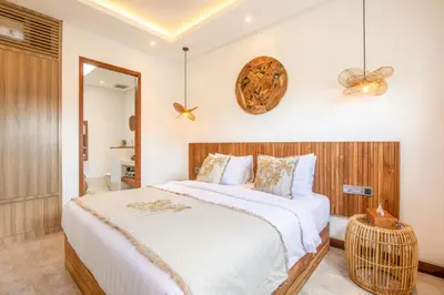 a bedroom with a large bed and a clock on the wall at Coastal Elegance 4BR Villa, 400m to Finns in Canggu