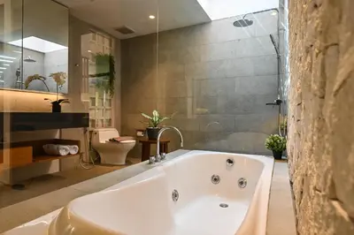 a bathroom with a tub and a shower and a toilet at The Cabana Villa in Seminyak