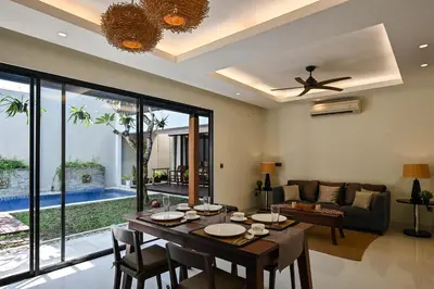 a dining room with a table and a couch at The Cabana Villa in Seminyak