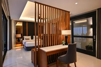 a bedroom with a bed and a desk with a chair at The Cabana Villa in Seminyak