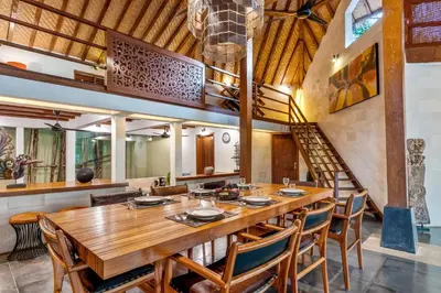 a dining room with a large wooden table and chairs at Villa Shantika by Villa Finder in Seminyak