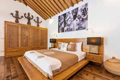 a bedroom with a large bed and wooden floors at Villa Shantika by Villa Finder in Seminyak