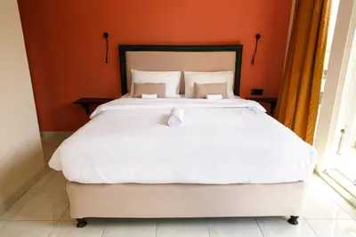 a bedroom with a large white bed with orange walls at Villa Majapahit Kuta 5 bedrooms in Legian