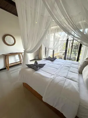 a bedroom with a large white bed with curtains at Villa CUCU - Legian - 3 Bedroom in Legian