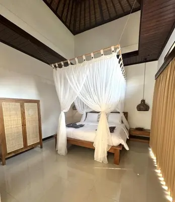 a bedroom with a canopy bed with white curtains at Villa CUCU - Legian - 3 Bedroom in Legian