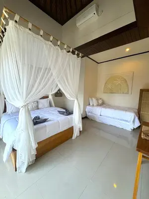 a bedroom with two beds with white drapes at Villa CUCU - Legian - 3 Bedroom in Legian