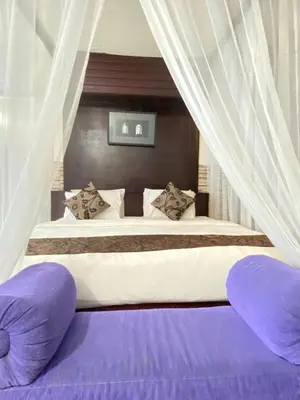 a bedroom with a large bed with purple pillows at One Bedroom Private Pool Classic Villa in Kuta
