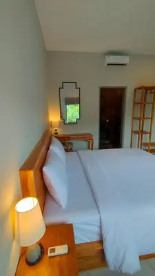 a bedroom with a bed and a table with a lamp at Aleenka House in Canggu
