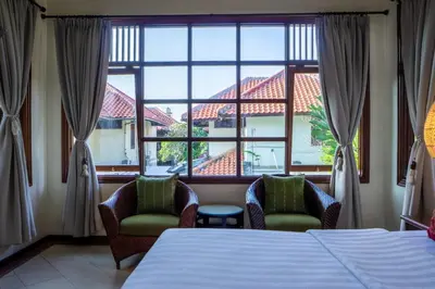 a bedroom with a bed and two chairs and a large window at Atres Griya Villa 5 Private Bedroom Kuta in Kuta