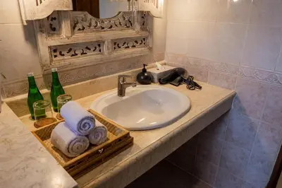 a bathroom sink with towels and bottles on a counter at Atres Griya Villa 5 Private Bedroom Kuta in Kuta