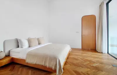 a bedroom with a bed with white sheets and wooden floors at Jipsi Villas Canggu in Canggu