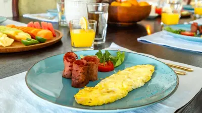 a blue plate with eggs sausage and vegetables on a table at Villa Latima by Villa Finder in Seminyak