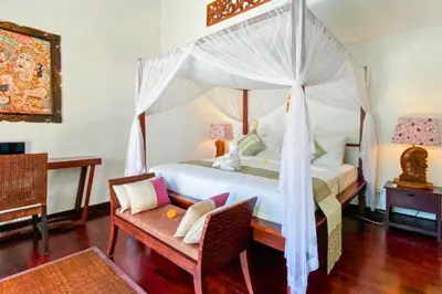 a bedroom with a canopy bed with a table and a chair at Chetana 2 BR Private Pool Villa in Ujung