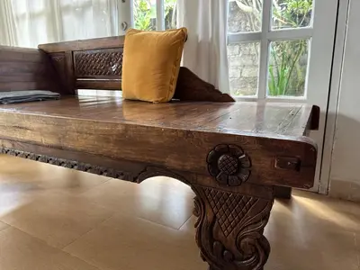 a wooden bench with a pillow on top of it at Cottage House Jimbaran in Jimbaran