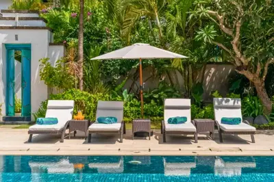 a group of chairs and an umbrella next to a pool at Chayanika 4 BR Private Pool Villa With Sea View in Ujung
