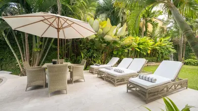 a patio with chairs and a table with an umbrella at Villa Celeste by Villa Finder in Seminyak