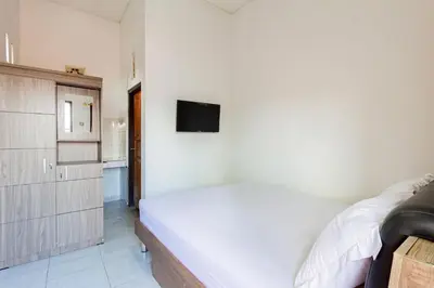 a bedroom with a bed and a tv on a wall at SN Guest House Near Trans Studio Mall in Legian