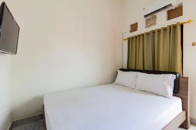 a bedroom with a white bed and a television at SN Guest House Near Trans Studio Mall in Legian