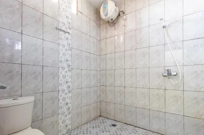 a bathroom with a shower with a toilet at SN Guest House Near Trans Studio Mall in Legian