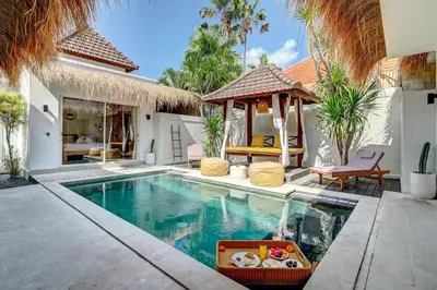 a swimming pool with a gazebo next to a house at Villa Esha II in Seminyak