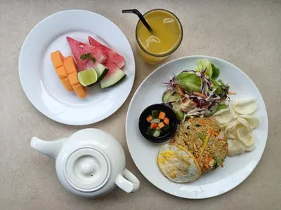 two white plates of food and a teapot and a plate of food at Privat Pool villa at kuta in Kuta