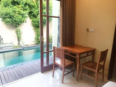 a table and chairs next to a window with a pool at Dana Villa Bali in Seminyak