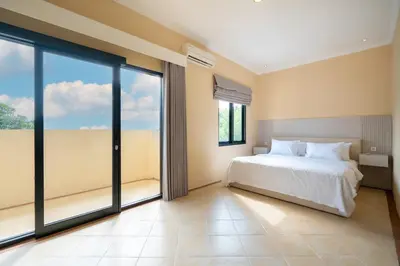 a bedroom with a bed and large sliding glass doors at Villa Uma Sari in Kerobokan