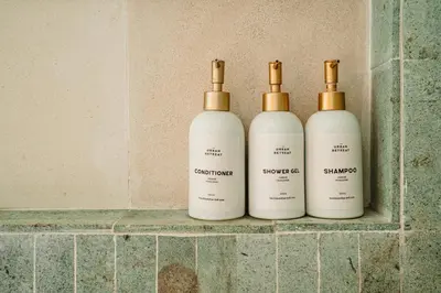 three bottles of shampoo sitting on a shelf in a bathroom at The Urban Retreat Seminyak Private Pool Villas with Butler for Families & Groups in Seminyak