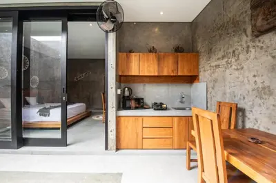 a kitchen with wooden cabinets and a bed in a room at Minimalist Villa with Pool #Nico1 in Canggu