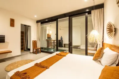 a bedroom with a large white bed and glass walls at Minimalist Villa with Pool #Lina2 in Canggu