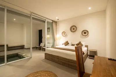 a bedroom with a bed and a glass wall at Minimalist Villa with Pool #Jade3 in Canggu