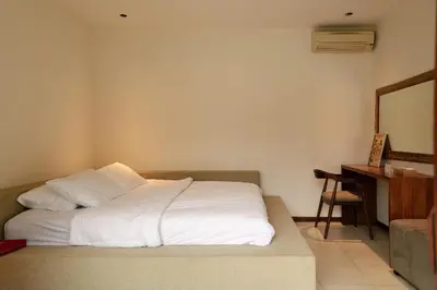 a bedroom with a bed with white sheets and a desk at Villa NUSA - 3BR Villa in Umalas next to Nook in Kerobokan