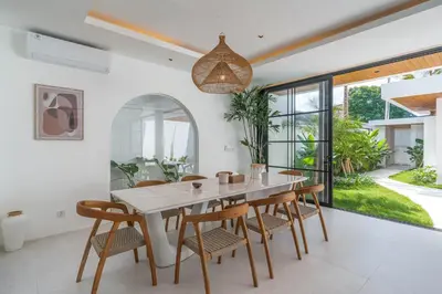 a dining room with a white table and chairs at Villa Jenna - Exquisite 3BR Villa Close to Batu Belig Beach in Canggu