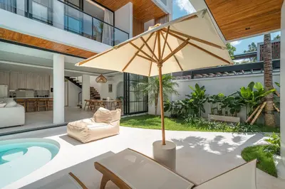 a patio with a table and an umbrella at Villa Jenna - Exquisite 3BR Villa Close to Batu Belig Beach in Canggu