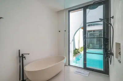 a bath tub in a bathroom with a large window at Villa Jenna - Exquisite 3BR Villa Close to Batu Belig Beach in Canggu
