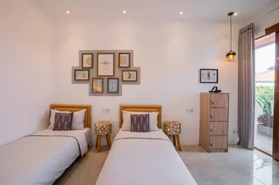 two beds in a room with white walls at NEW! Villa Sony 1 - 3BR Villa next to Legian Beach in Seminyak