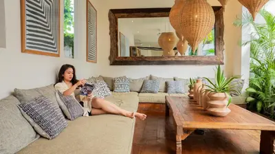 a woman sitting on a couch in a living room at Villa Elita - Modern Stylish 4BR Villa with Rooftop Lounge, 12 Minutes to the Beach in Kerobokan
