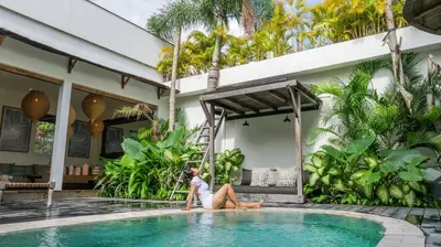 a woman sitting in a swimming pool in a house at Villa Elita - Modern Stylish 4BR Villa with Rooftop Lounge, 12 Minutes to the Beach in Kerobokan