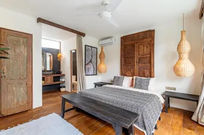 a bedroom with a bed and a wooden door at Villa Elita - Modern Stylish 4BR Villa with Rooftop Lounge, 12 Minutes to the Beach in Kerobokan