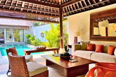 a living room with a couch and a table and a pool at Dilana 2 BR Bamboo Villas JU66 in Seminyak