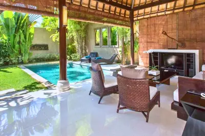 a living room with a fireplace and a swimming pool at Nisara 2 BR Garden Pool Villas JU67 in Seminyak