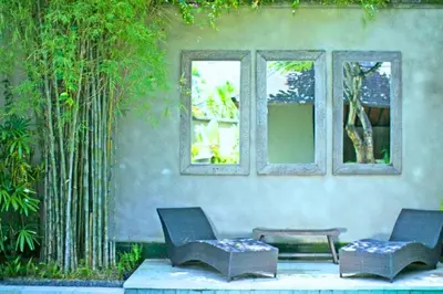 two chairs and a bench in front of a building at Nisara 2 BR Garden Pool Villas JU67 in Seminyak
