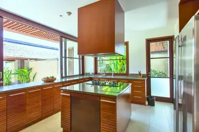 a kitchen with wooden cabinets and a counter top at Neada 4 BR Grand Pool Villa JU68 in Seminyak