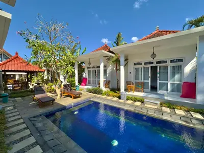 a swimming pool in front of a house at Bali Stuti Jimbaran Inn in Jimbaran