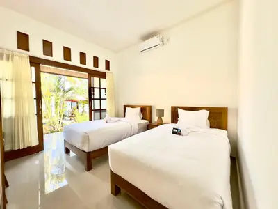 a bedroom with two beds and a window at Bali Stuti Jimbaran Inn in Jimbaran